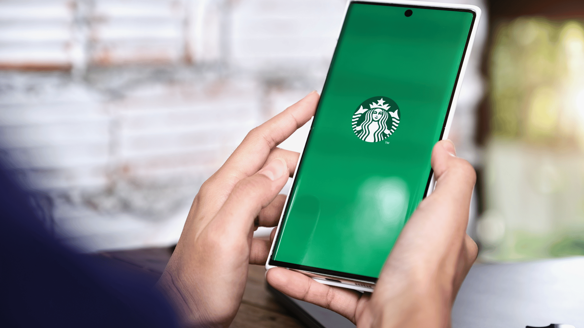 Person holding a phone with the Starbucks app loading