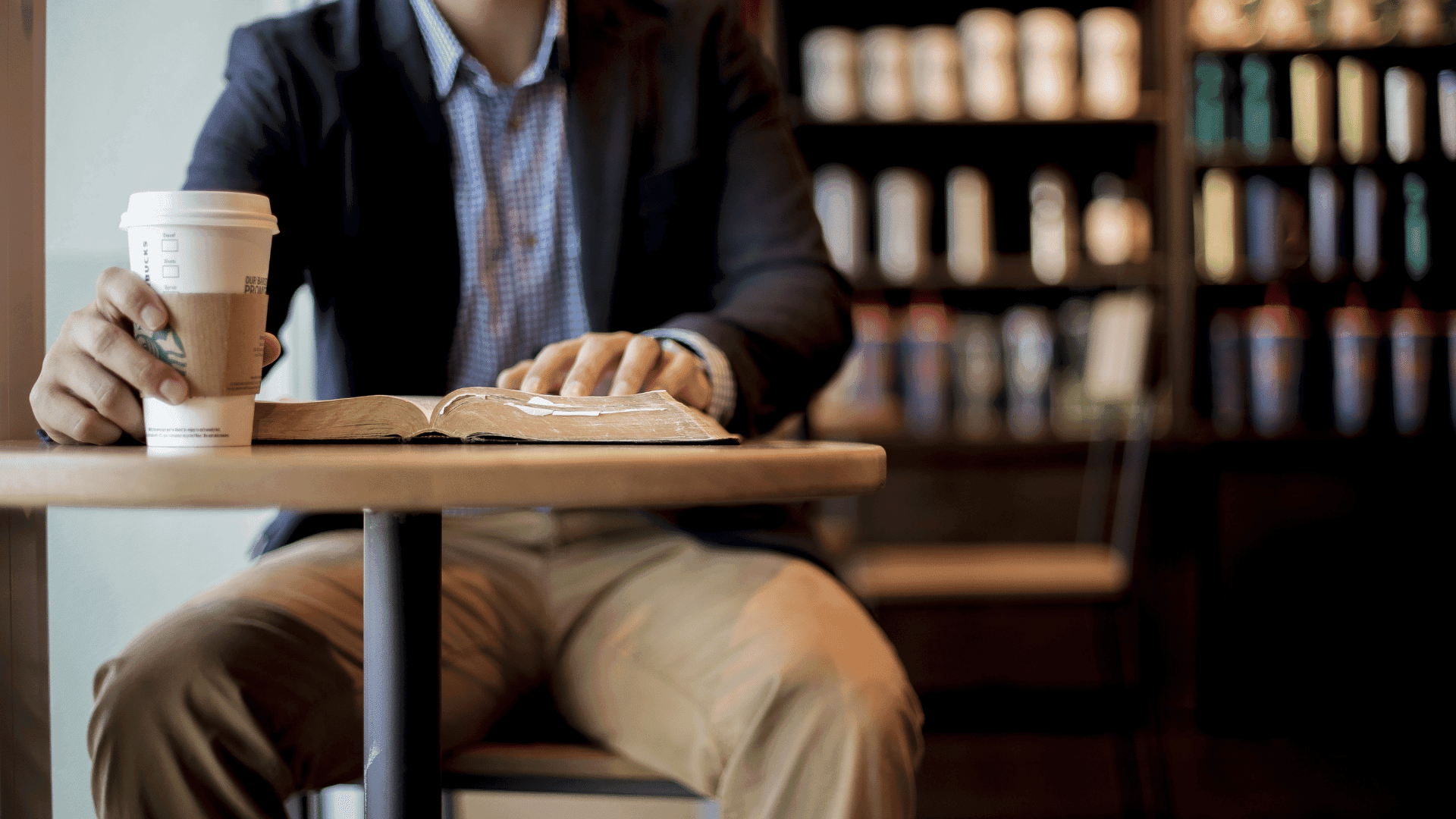 Man reading while drinking a Starbucks coffee in-store