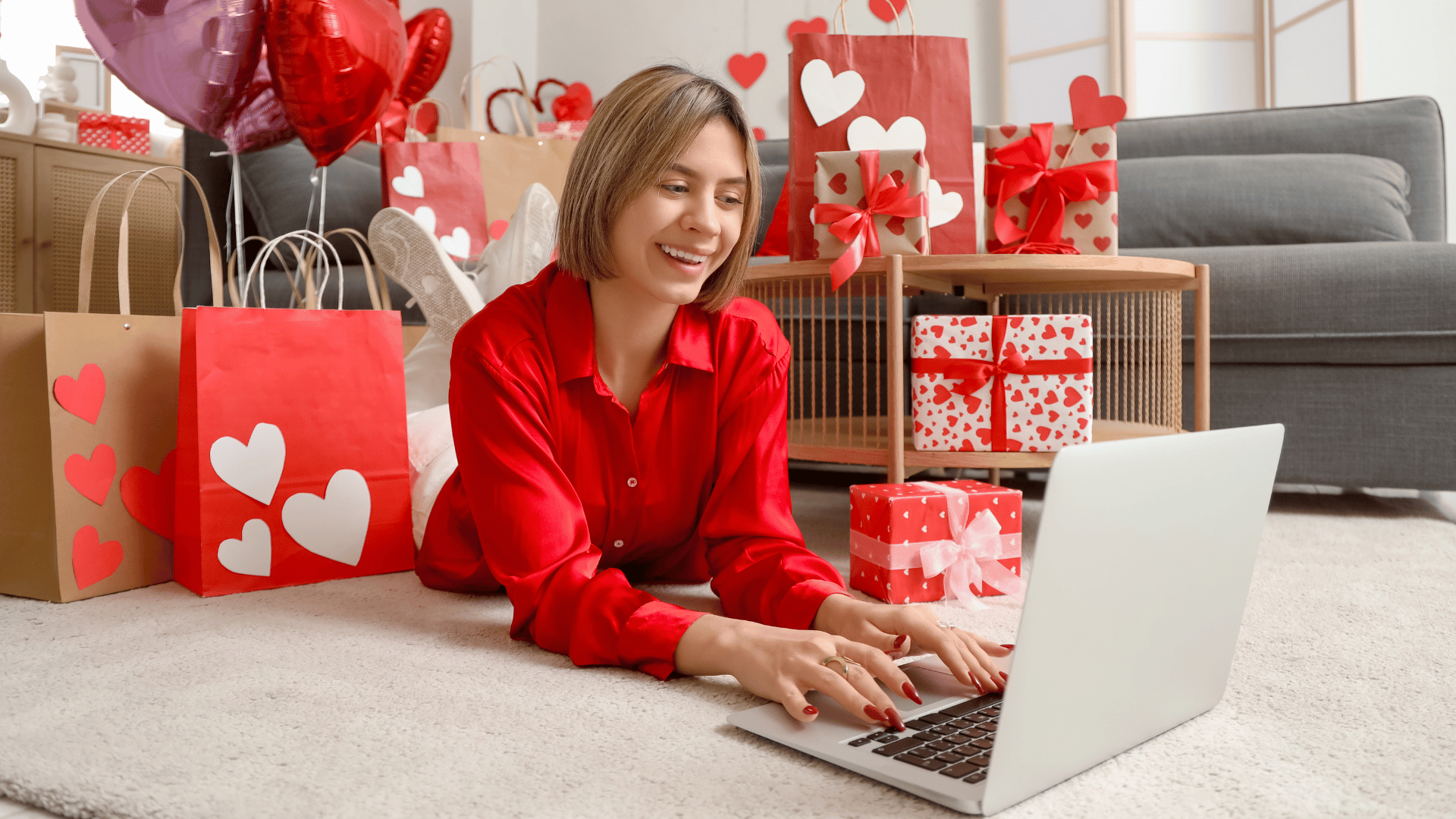 Woman on the floor on her computer with Valentine's Day decor in the background
