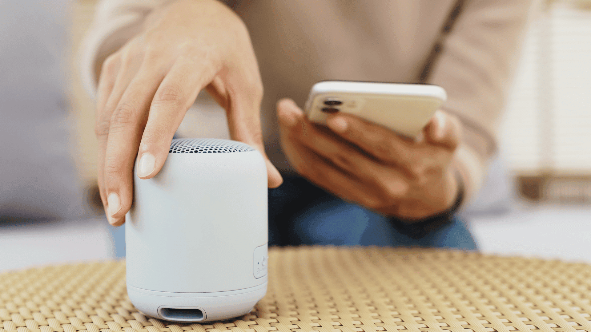 A woman holding a smartphone and Bluetooth speaker
